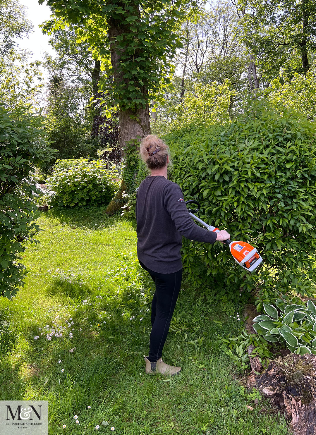 Melanie with a battery powered hedge trimmer in the garden